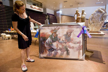 Inter-Tribal Indian Ceremonial board member Lisa Rodriguez shows off a painting by Johnson Yazzie that was awarded this year's Best in Show prize Monday at Red Rock Park. © 2011 Gallup Independent / Cable Hoover 
